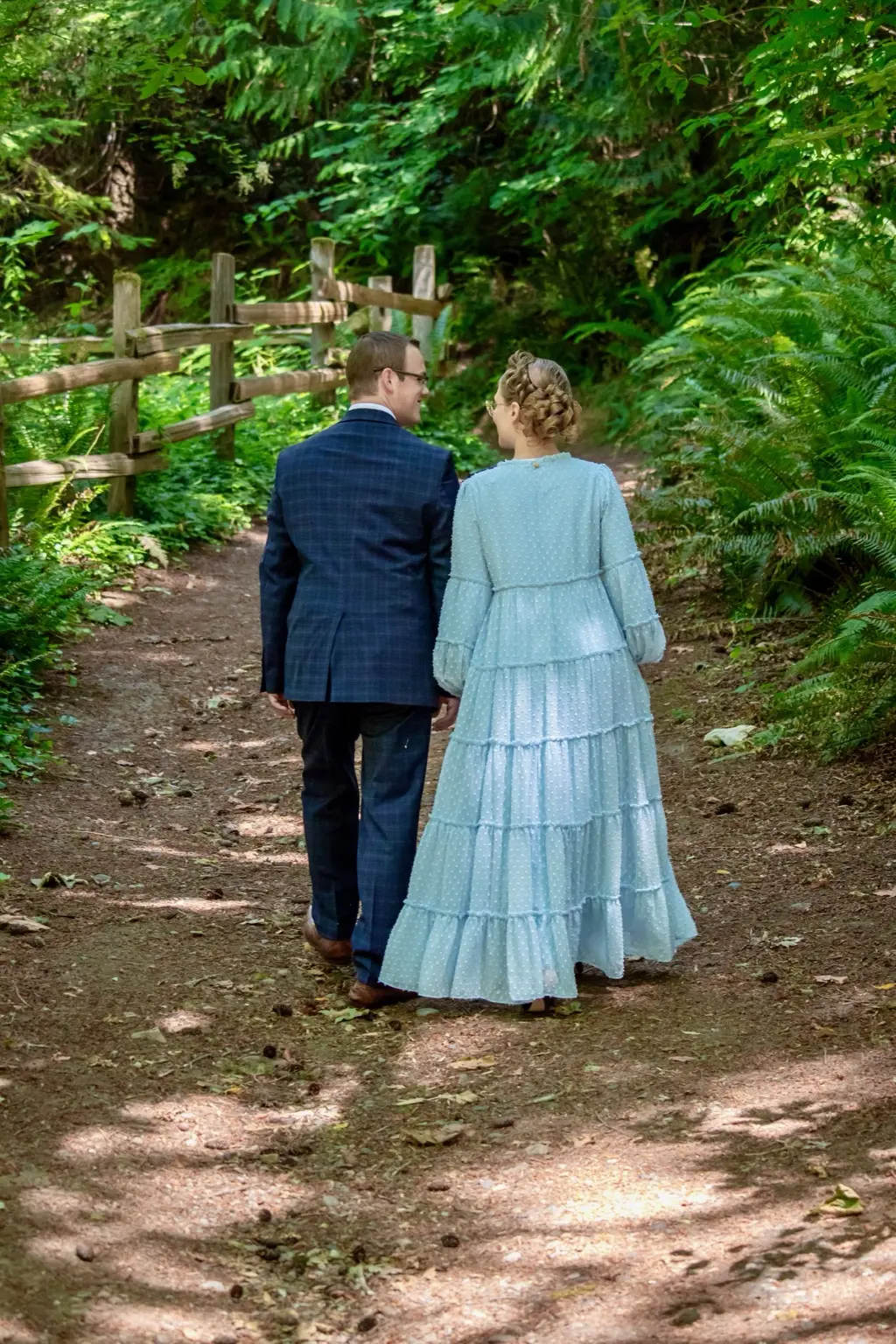 Alyssa and Caleb walking hand in hand on a forest path
