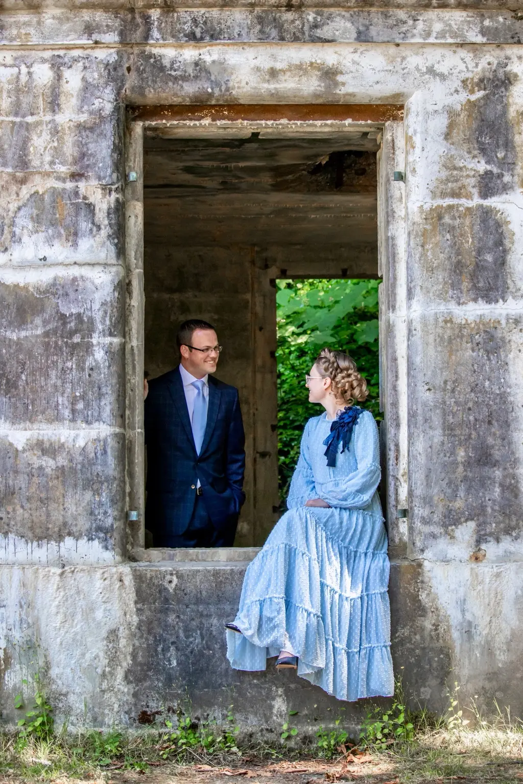 Alyssa and Caleb smiling at one another through a rustic window